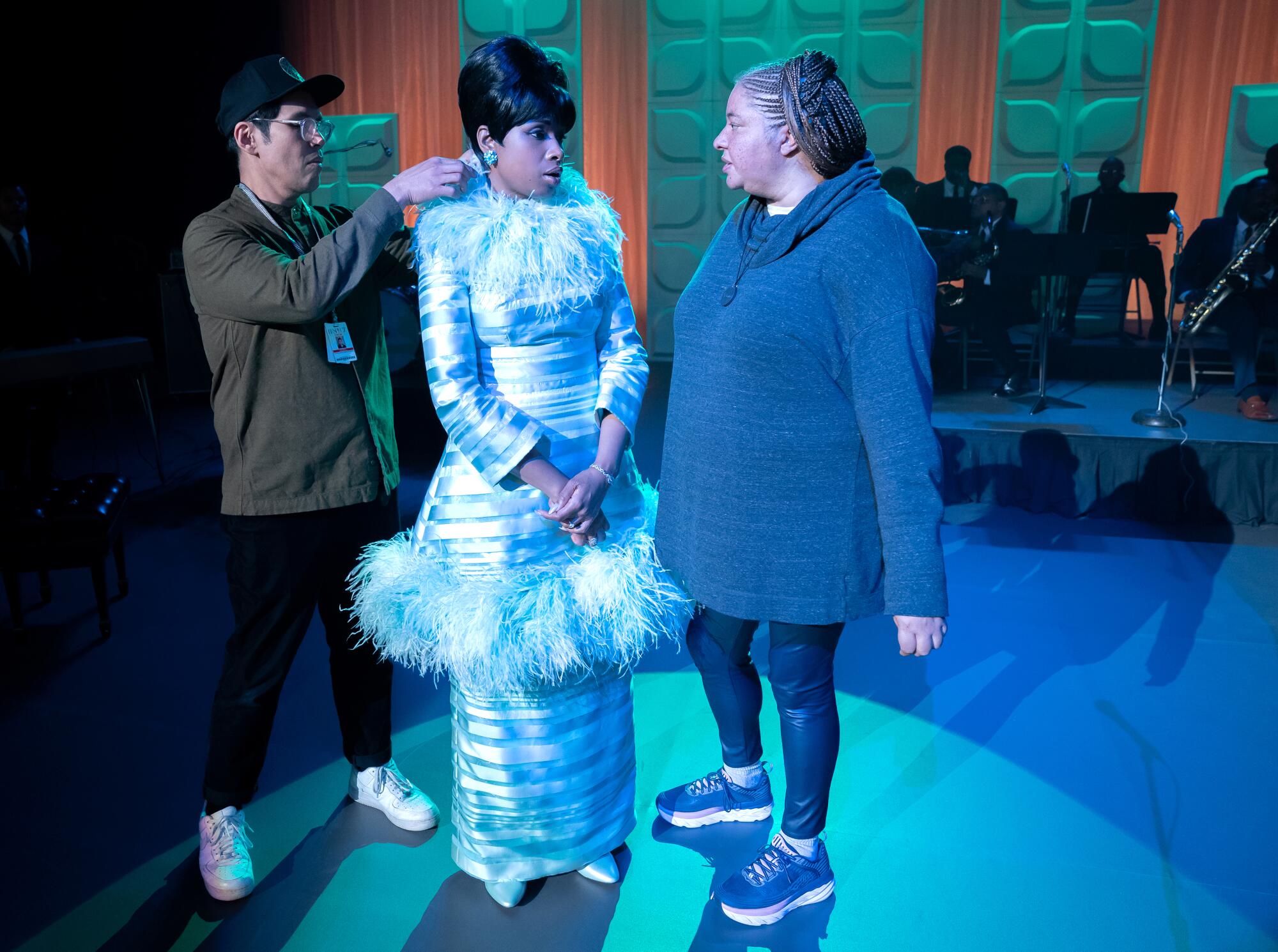 Costume designer Clint Ramos adjusts Jennifer Hudson's full-length silver gown as she talks with director Liesl Tommy.