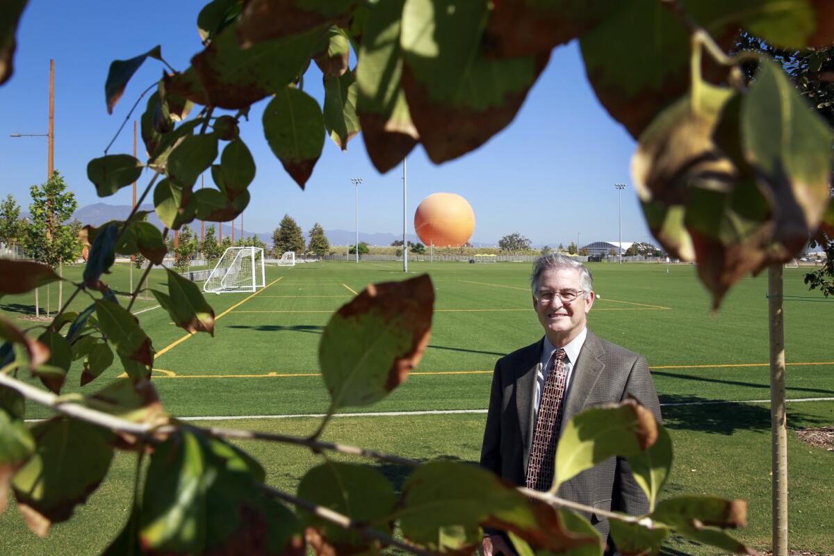 Larry Agran, a former mayor of Irvine, stands aside soccer fields at the Great Park with the facility's signature orange balloon in the background.