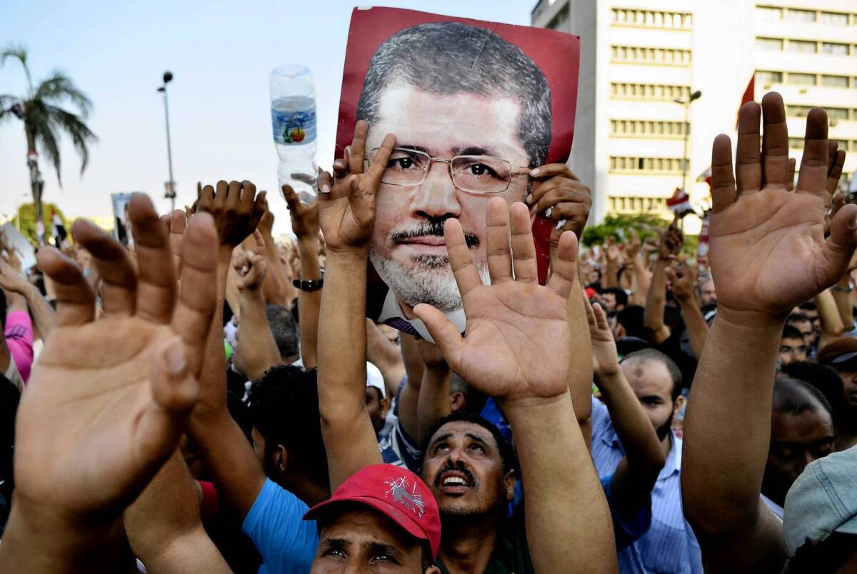 Egyptian supporters of the Muslim Brotherhood hold pictures of deposed President Mohamed Morsi outside the Republican Guard headquarters in Cairo. His ouster has rekindled debate about whether the Obama administration’s Mideast policy has been too passive.