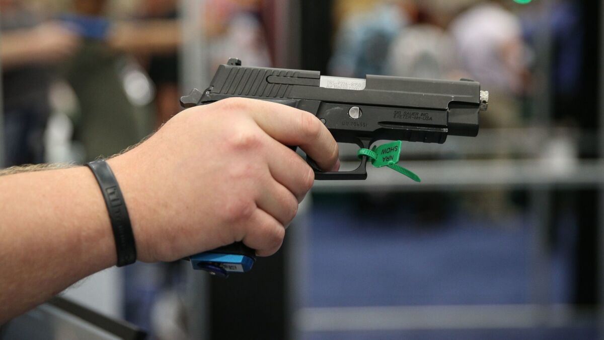 A man test aims a pistol at the National Rifle Assn. convention in Dallas on May 6.