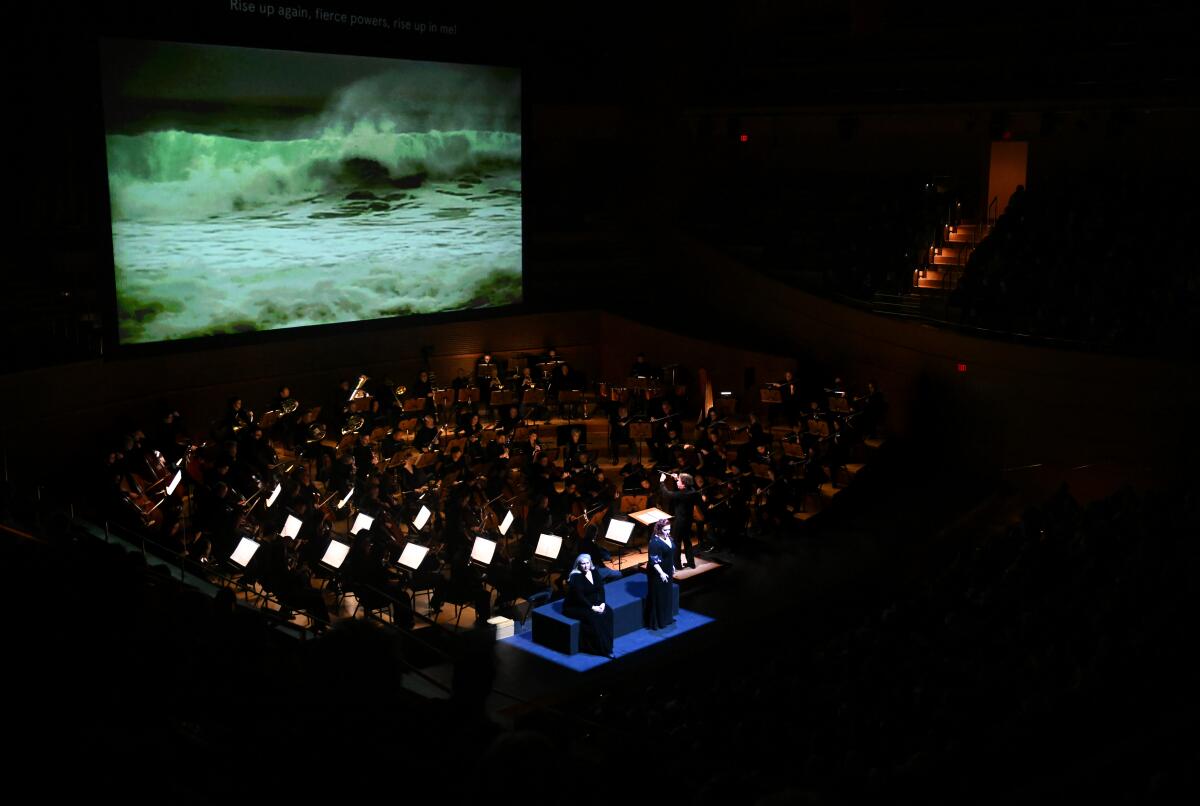 The L.A. Phil performers in front of a massive video of a roiling sea