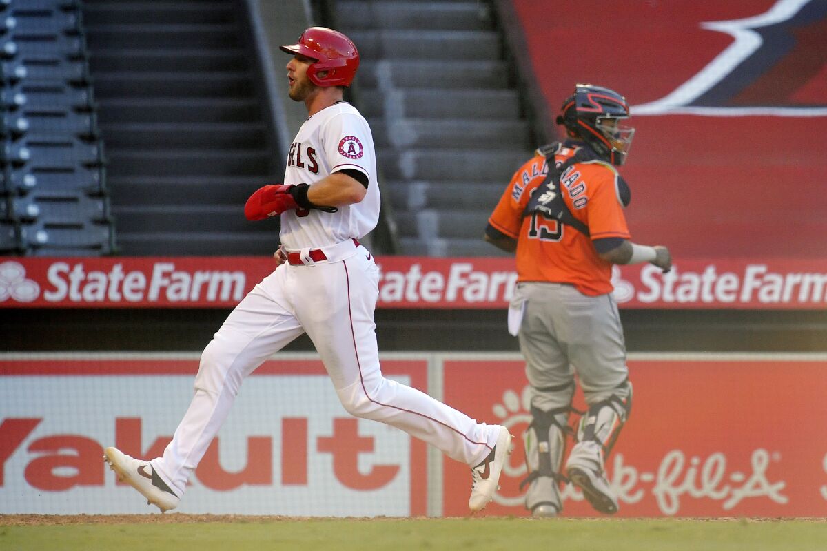 Los Angeles Angels' Taylor Ward, left, scores on a sacrifice fly by David Fletcher as Houston Astros catcher Martin Maldonado stands near the plate during the sixth inning of a baseball game Saturday, Aug. 1, 2020, in Anaheim, Calif. (AP Photo/Mark J. Terrill)