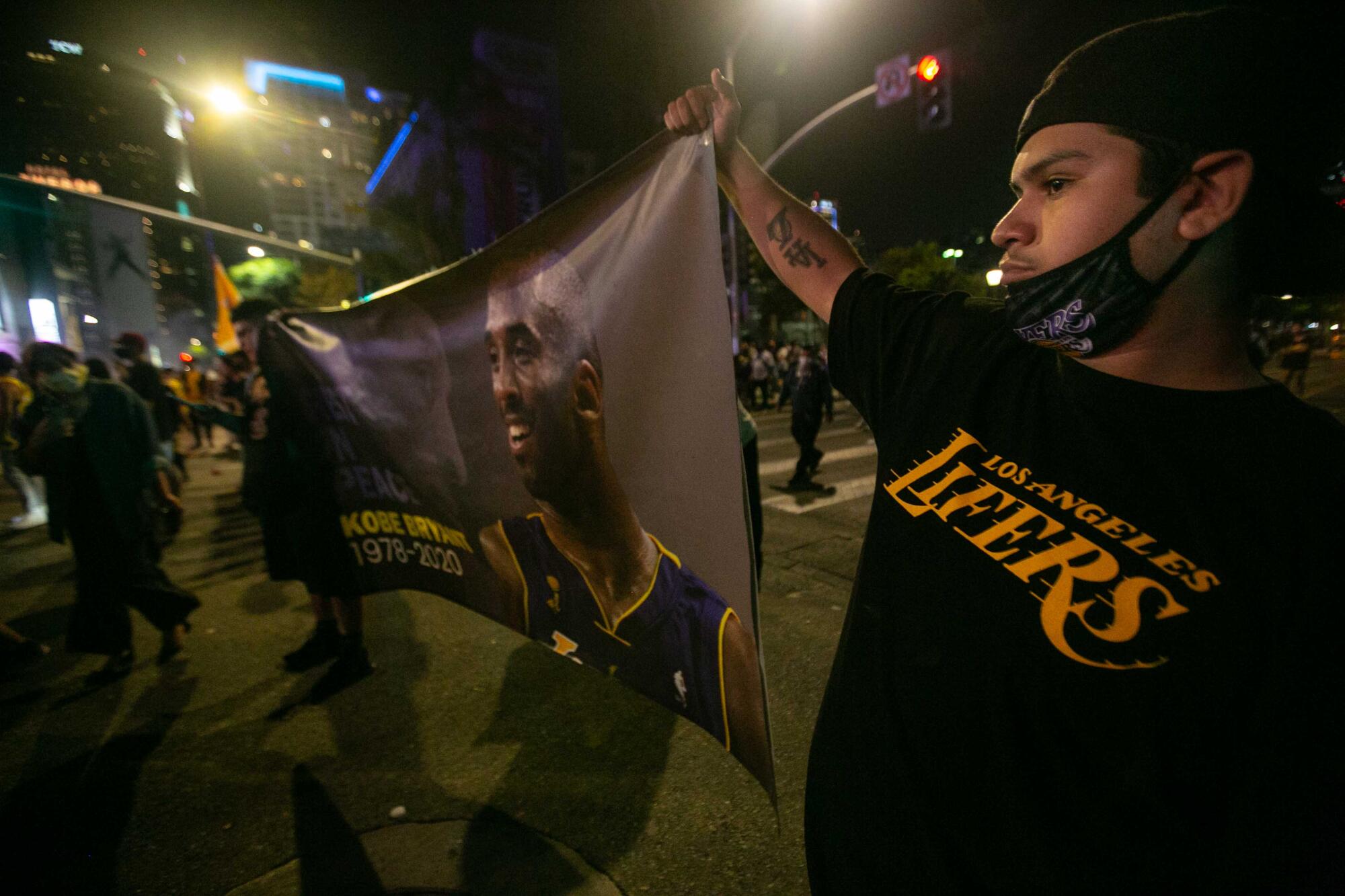 Los Angeles Lakers fans hold a banner of deceased Laker Kobe Bryant as they gather near the Staples Center
