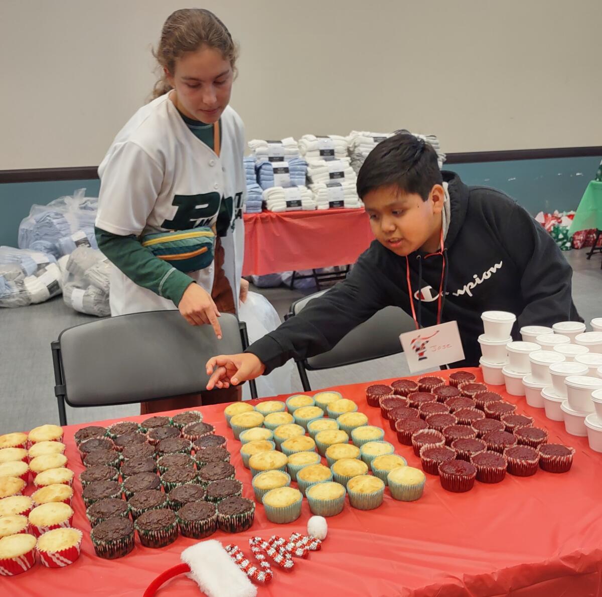 Jose Martinez reaches for a cupcake to decorate with the help of Anjolie Norton.