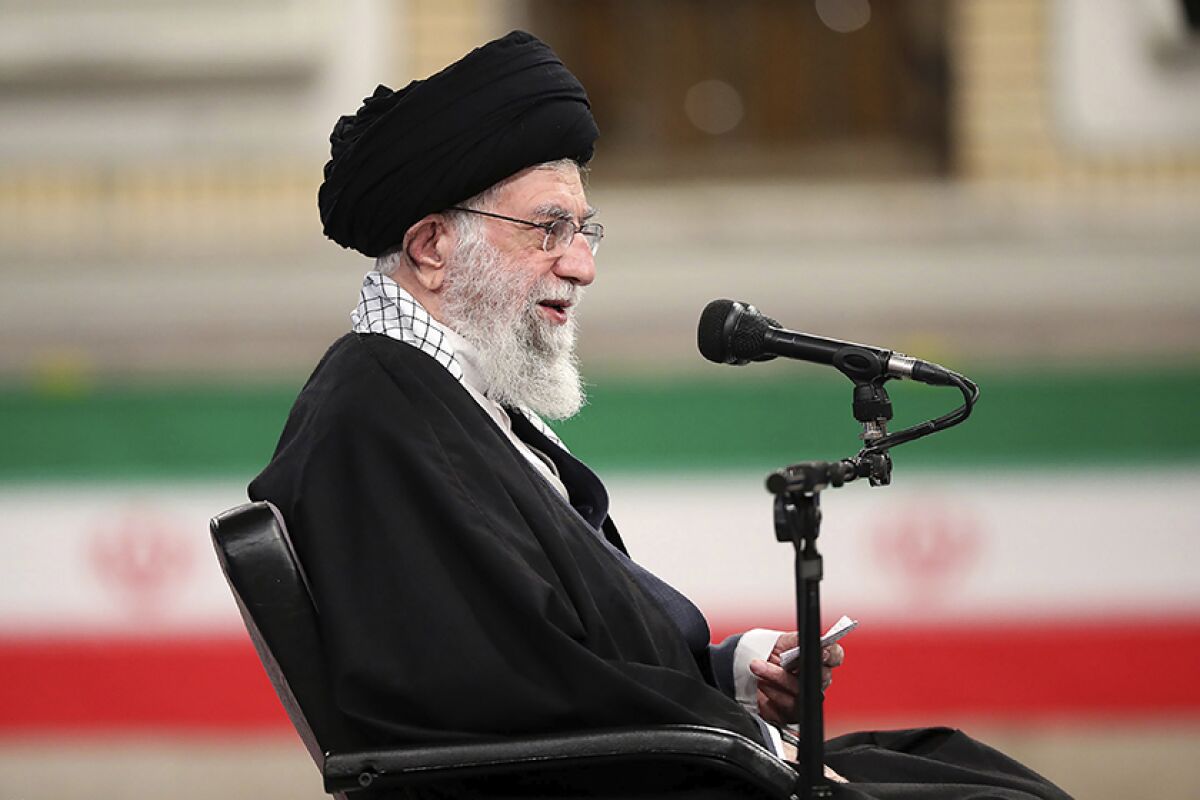 Khamenei speaks into a microphone while seated on a stage.