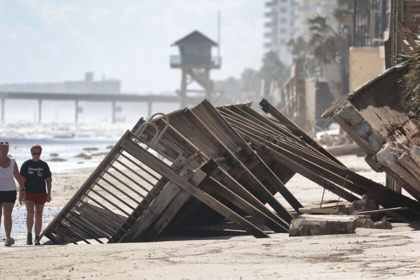 Beachgoers survey the damage Monday, Oct. 3, 2022, in Daytona Beach Shores, Fla., as hotel and condo seawalls and pool decks along the Volusia County coastline were gutted by Hurricane Ian last week. (Joe Burbank/Orlando Sentinel via AP)