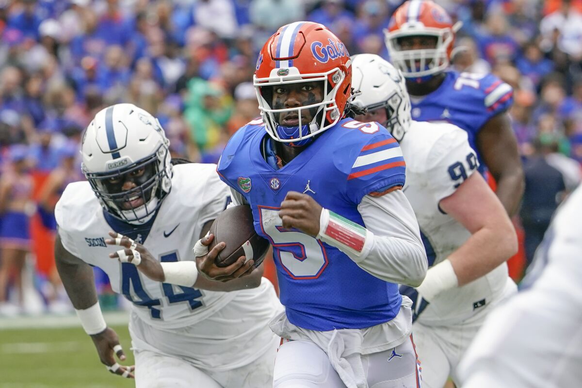 Florida quarterback Emory Jones (5) scores a touchdown on a 31-yard run as he gets past Samford defender Tay Berry, left, and defensive tackle Seth Simmerduring the first half of an NCAA college football game, Saturday, Nov. 13, 2021, in Gainesville, Fla. (AP Photo/John Raoux)