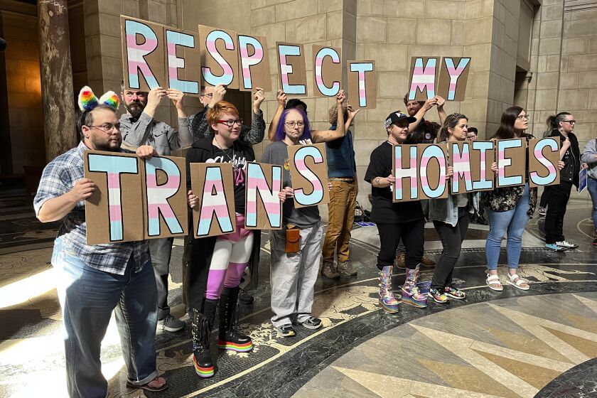 A group of around 200 people who turned out for a rally inside the Nebraska State Capitol hold up signs in support of the transgender community, Friday, March 24, 2023 in Lincoln, Neb. The rally was held to protest the advancement of a bill Thursday that would ban gender-affirming care for minors, as well as a bill that would criminalize allowing minors to attend drag shows. (AP Photo/Margery Beck)