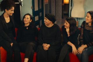 Five women sit on a red couch.