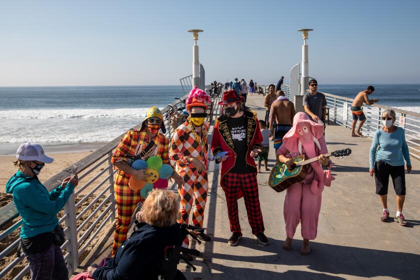 HERMOSA BEACH, CA - NOVEMBER 26: Tony Drockton, of Hermosa Beach, left, is joined, from left, by his nephew Daniel, son Riley (in red) and niece Deanna (on guitar), as they serenade passersby with a "Thanksgiving Song," on the Hermosa Beach Pier, Thanksgiving day, in Hermosa Beach, CA, Thursday, Nov. 26, 2020. (Jay L. Clendenin / Los Angeles Times)