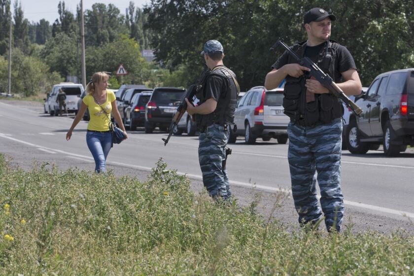 Pro-Russia gunmen flank a convoy of international forensic experts, police officers and security monitors in Shakhtarsk, Ukraine. The team was forced by nearby gunfire to halt 20 miles short of the Malaysia Airlines Flight 17 crash site.
