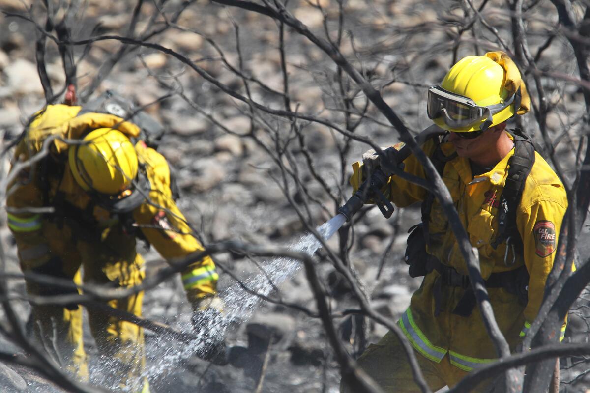 Firefighters mop up along Lower Gas Point Road after the Clover fire in Shasta County.