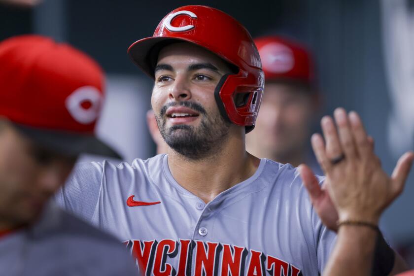 Cincinnati Reds' Christian Encarnacion-Strand celebrates with teammates in the dugout after scoring on a single by Jonathan India during the forth inning of a baseball game against the Texas Rangers in Arlington, Texas, Saturday, April 27, 2024. (AP Photo/Gareth Patterson)