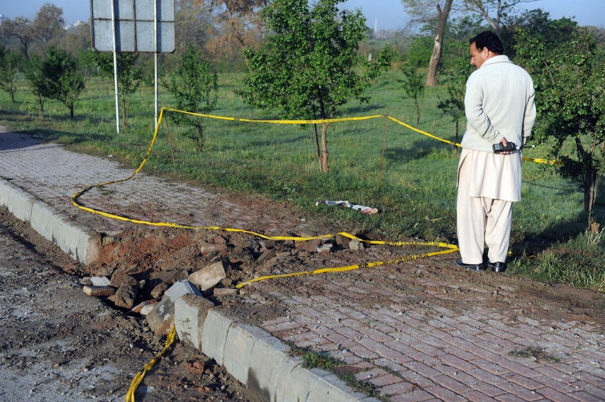 A Pakistani security official inspects the site of a bomb explosion in Islamabad that was apparently aimed at former military ruler Pervez Musharraf, who is on trial for treason.