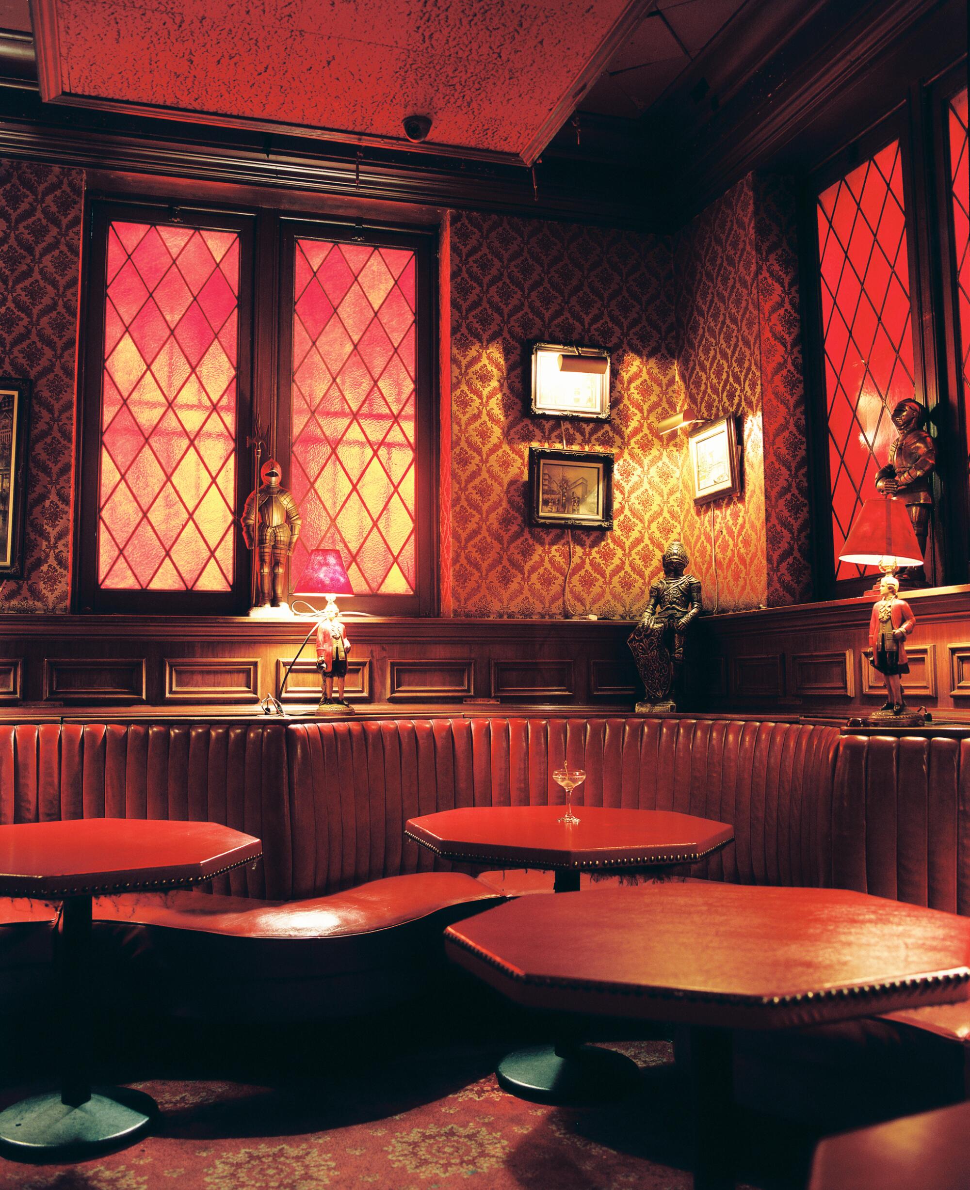 A photo of empty restaurant booths bathed in a red light.
