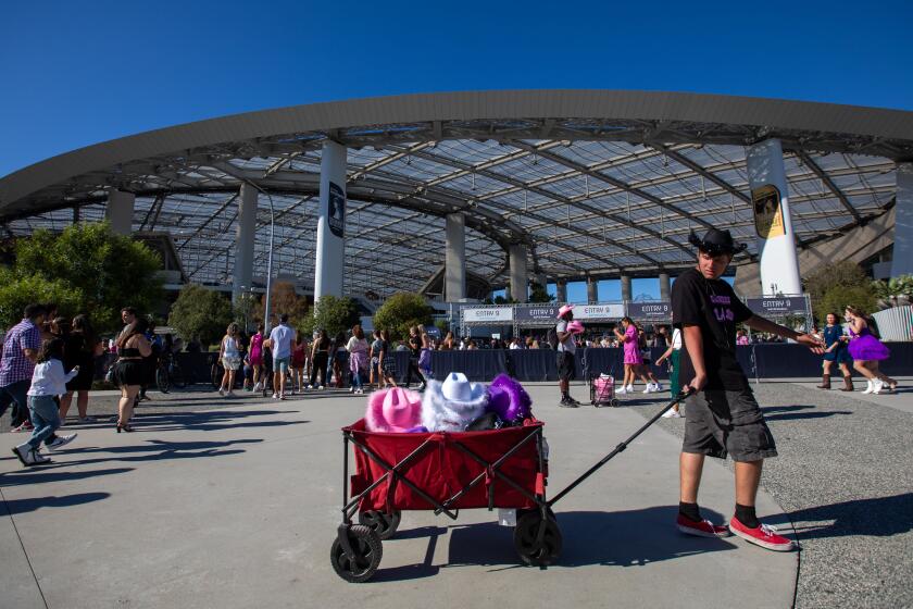 Inglewood, CA - August 03: A man sells hats out of a cart as Taylor Swift fans arrive at SoFi Stadium on Thursday, Aug. 3, 2023, in Inglewood, CA. Taylor Swift's fans arrive for the first of six sold-out Taylor Swift's Eras tour at SoFi Stadium. (Francine Orr / Los Angeles Times)