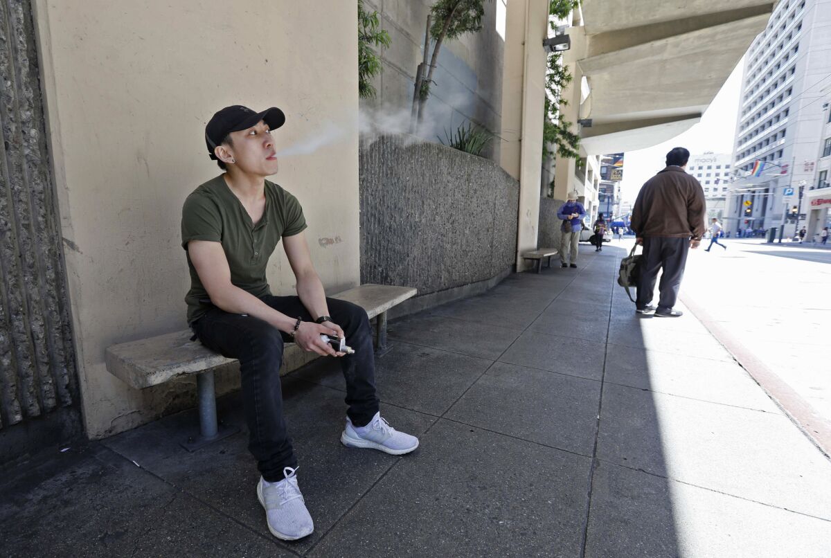 A man takes a vaping break from his job at a smoke shop in San Francisco.