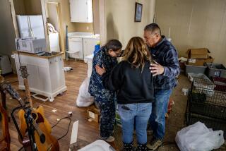 VALLEY OF ENCHANTMENT, CA - MARCH 24, 2023: Volunteers with Operation Mountain Strong Rita Nelson, middle, and Pastor Sal Martinez pray for Virginia Hauser, 70, left, whose trailer has partially collapsed but she refuses to leave her 11 cats in the Valley of Enchantment on March 24, 2023 in San Bernardino Mountains, California. Hauser's trailer was badly damaged under the weight of the recent heavy snowfalls. Operation Mountain Strong is trying to find homes for Houser's cats and also a safer place for her live. The organization brought her food and also food for her cats.(Gina Ferazzi / Los Angeles Times)