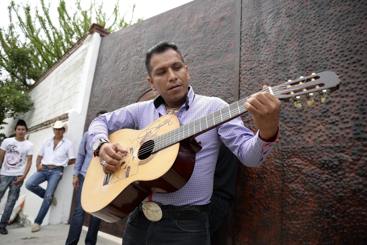 Domingo David, un admirador de Joan Sebastian, toca la guitarra afuera de la casa del cantante mexicano en Teacalco, México, el martes 14 de julio del 2015. Joan Sebastian murió el lunes tras una larga lucha con el cáncer. Tenía 64 años. (AP Foto/Tony Rivera)