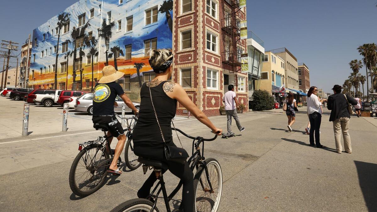 People walk or cycle along the Venice Beach Boardwalk, also known as Ocean Front Walk, in June 2018.