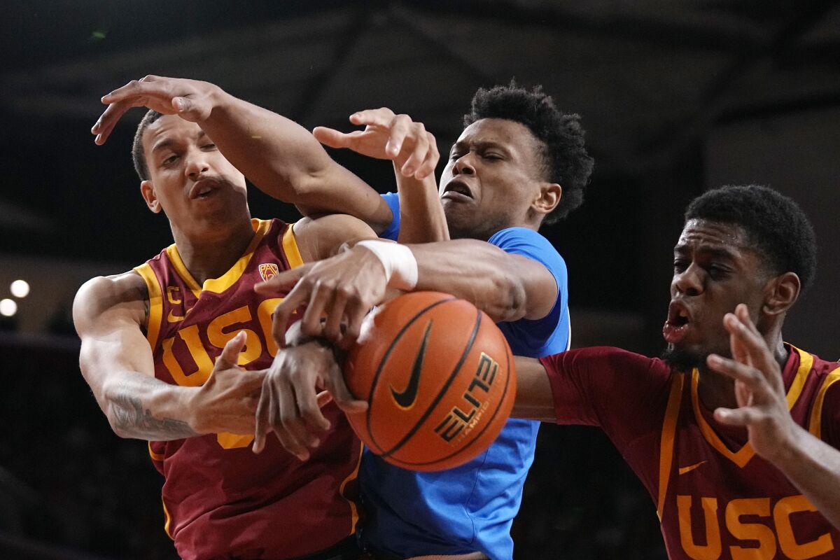 Southern California forward Kobe Johnson, and forward Joshua Morgan, right, battle for a rebound with UCLA guard Jaylen Clark during the first half of an NCAA college basketball game Thursday, Jan. 26, 2023, in Los Angeles. (AP Photo/Mark J. Terrill)