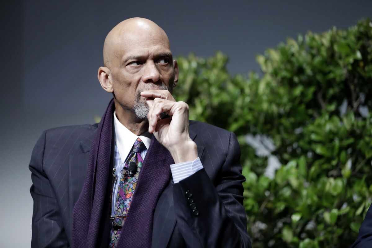 Kareem Abdul-Jabbar listens with his hand at his chin.