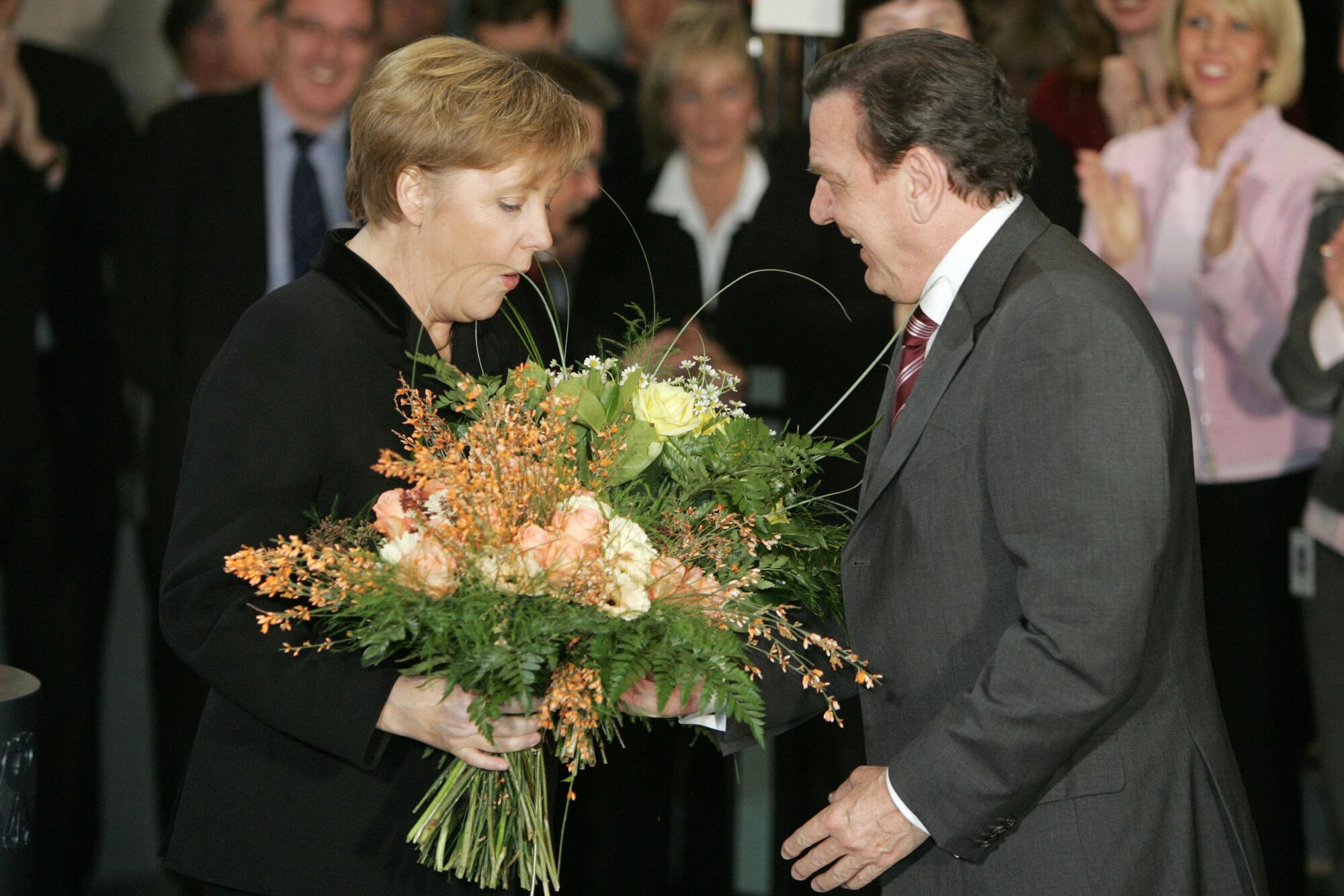 New Chancellor Angela Merkel is given a bouquet of flowers by outgoing Chancellor Gerhard Schroeder in 2005
