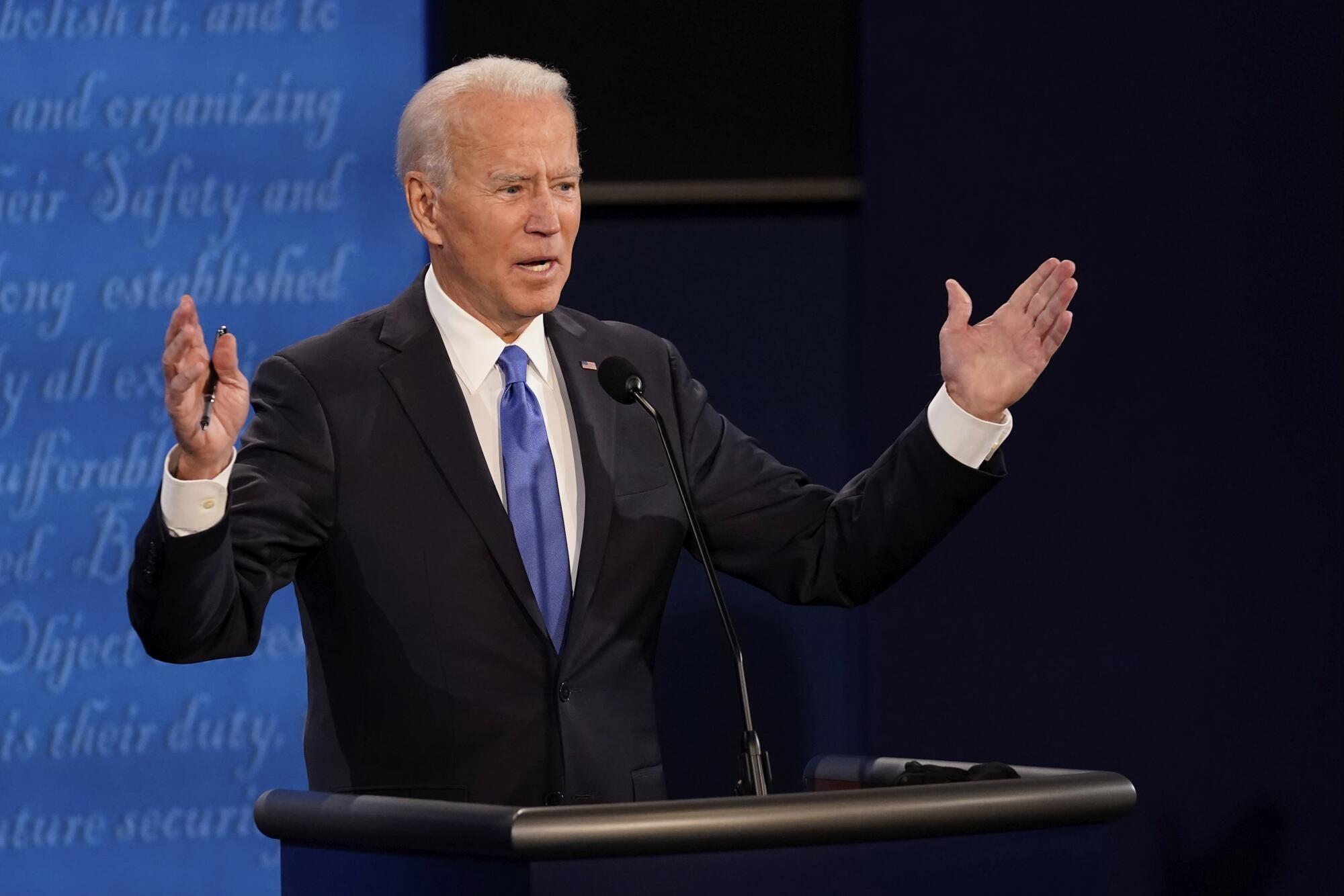 Joe Biden gestures with both hands as he speaks on stage