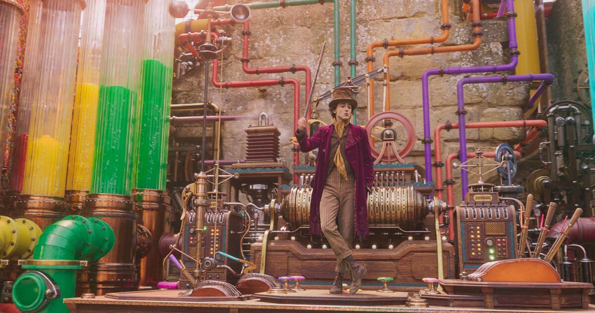 A man in a purple coat stands in his chocolate factory.