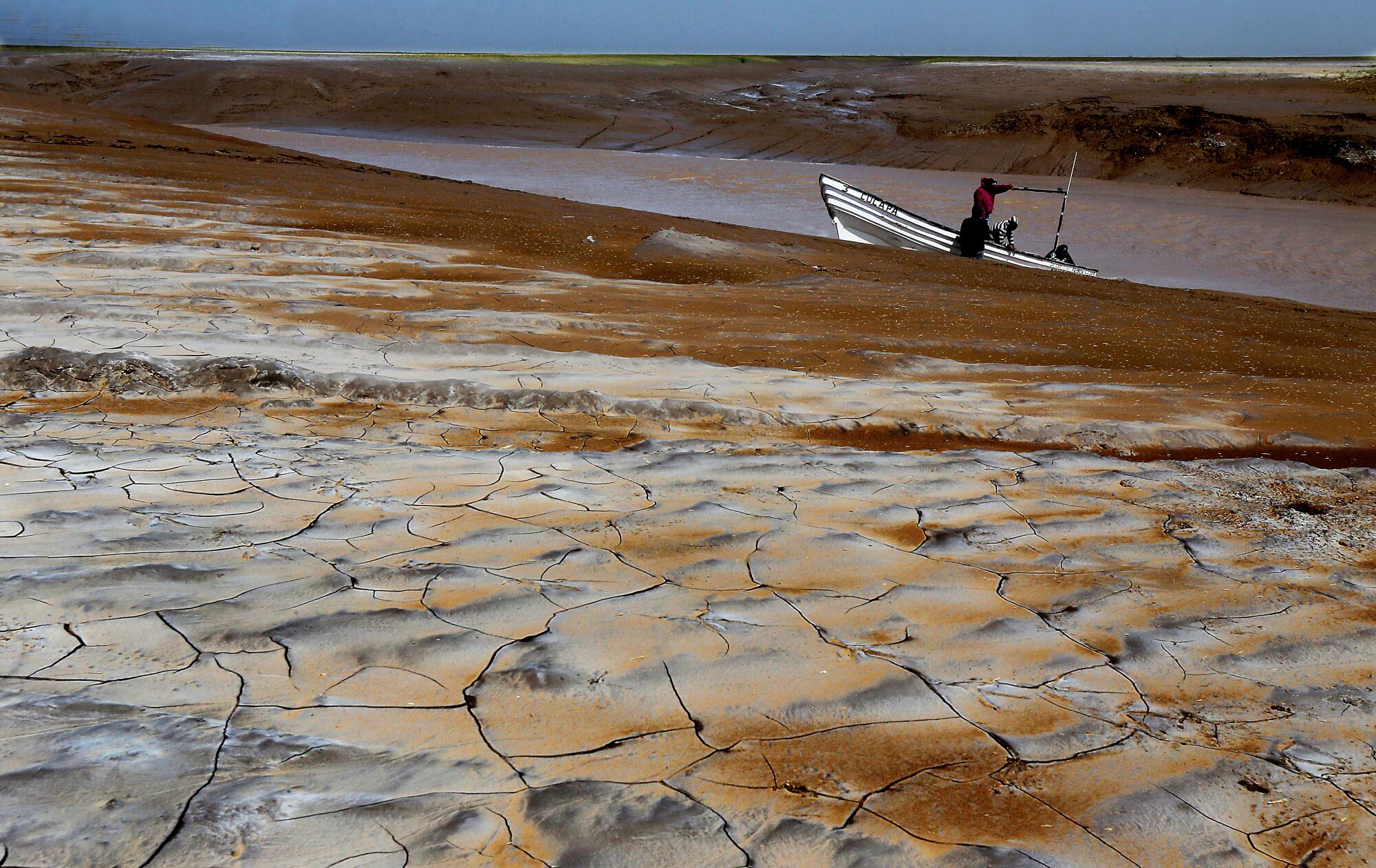 Fishermen wait for the tide to rise and lift their boat out of the muddy flats on the southern end of the Colorado River