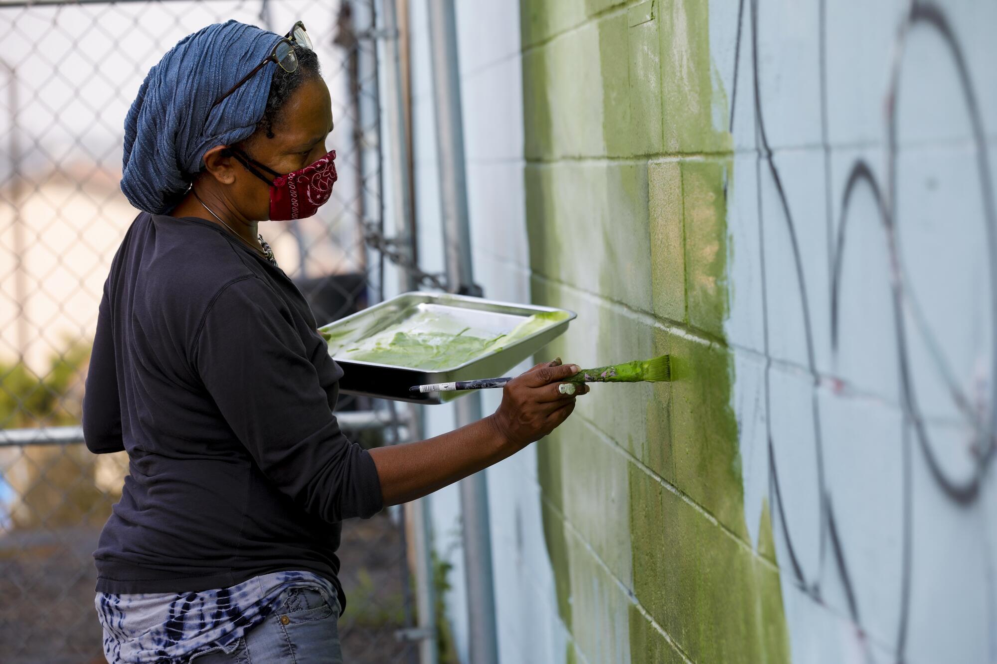 Ami Young-Hill paints the start of the foliage work on  one of the mural wall panels.