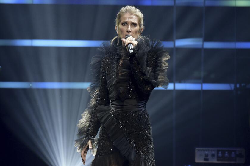 A woman in a ruffled black gown performs onstage