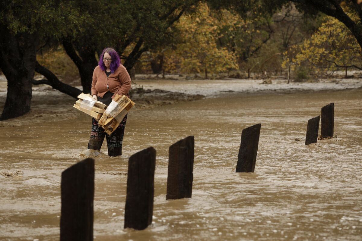 Ashley Ward carries fire wood from her campsite that was flooded by a creek that overflowed.