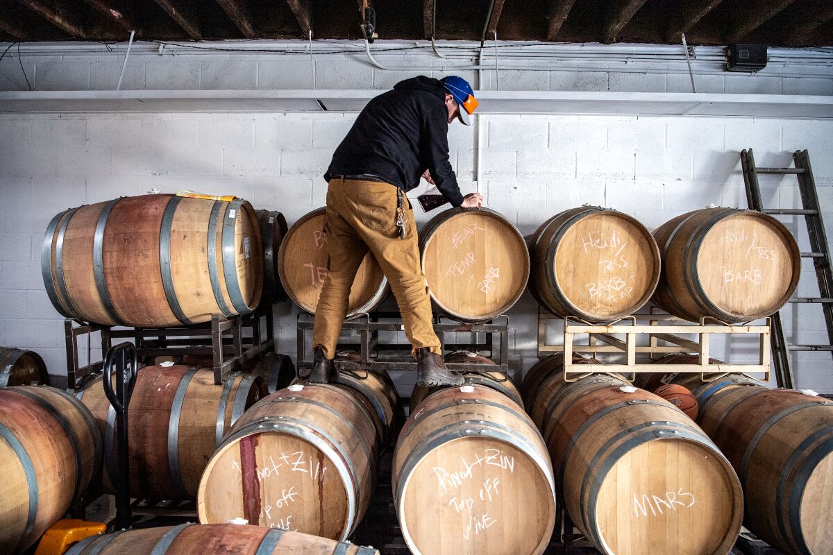 Adam Vourvoulis stands on wine barrels at Good Luck Wine Shop in East Pasadena.