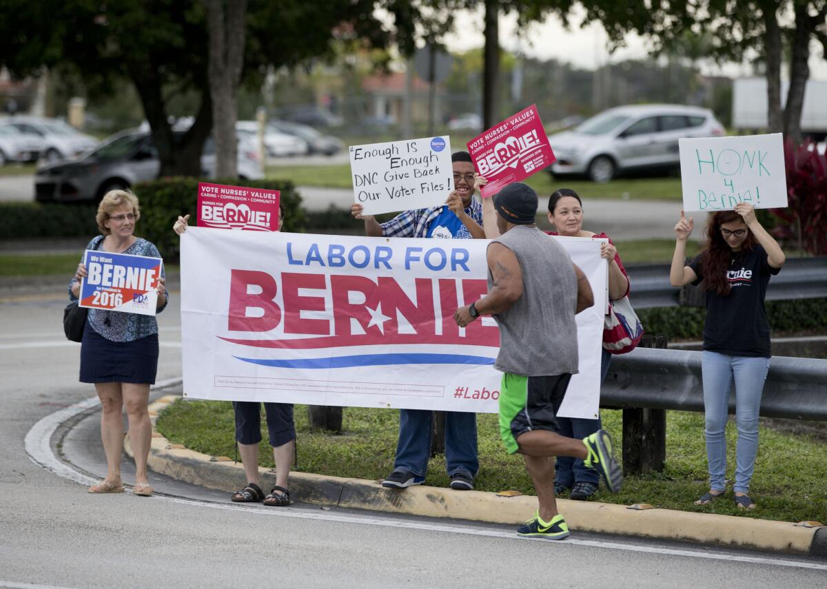 A jogger passes a handful of Bernie Sanders supporters outside Rep. Debbie Wasserman Schultz's district office Friday in Pembroke Pines, Fla.