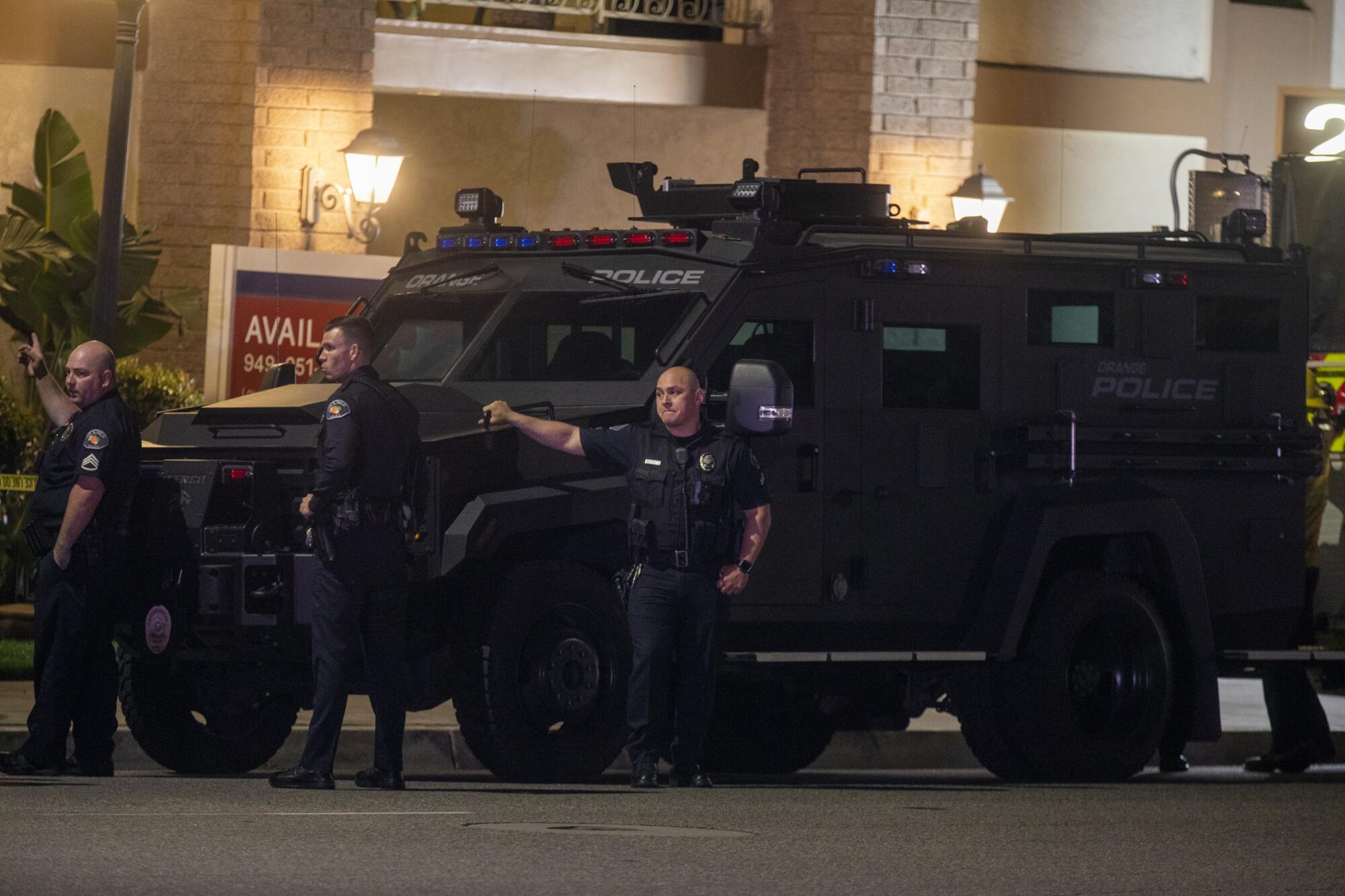 Three officers alongside a SWAT vehicle.