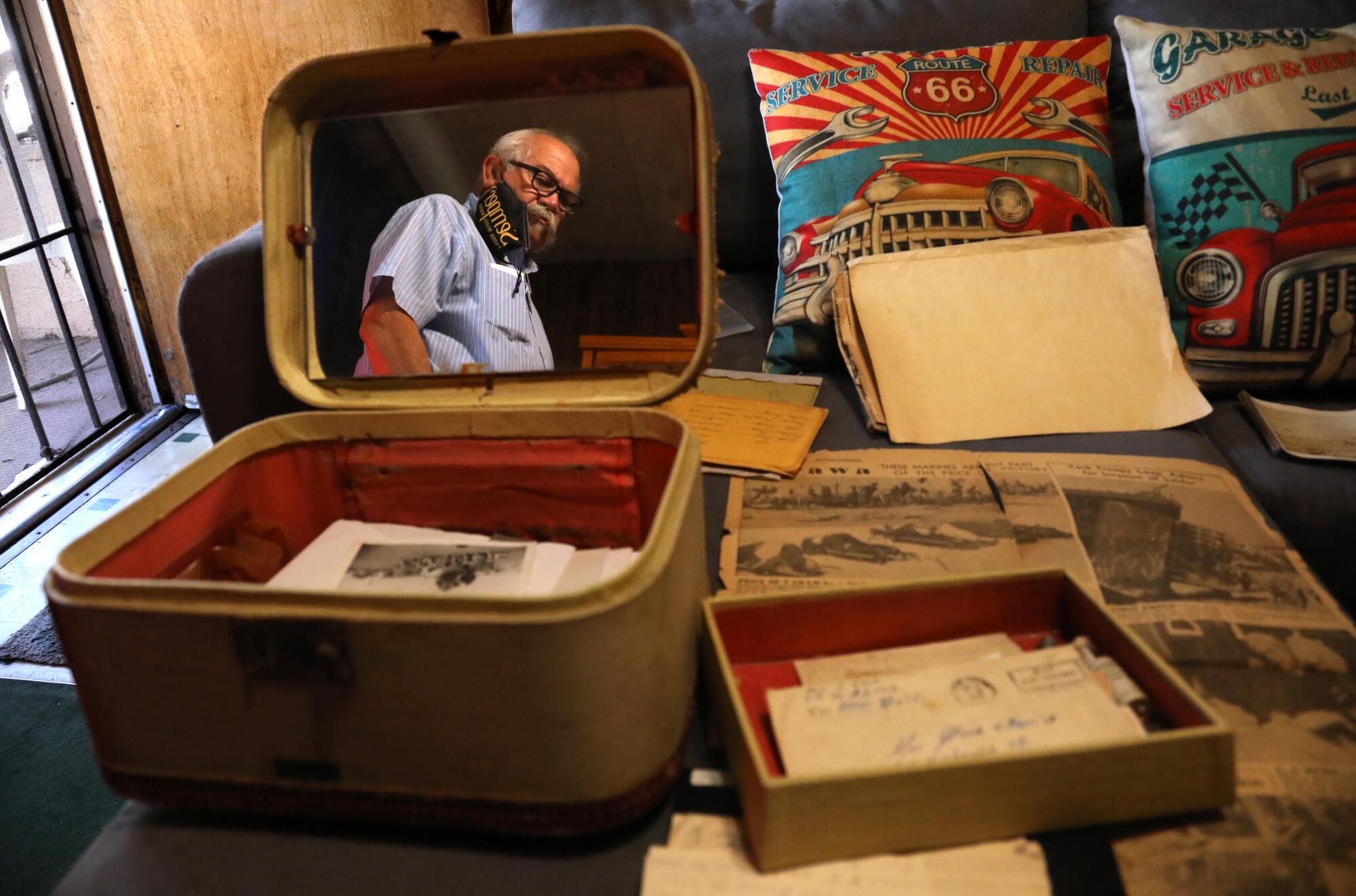 A man is reflected in the mirror of a cosmetics case containing photos and letters.