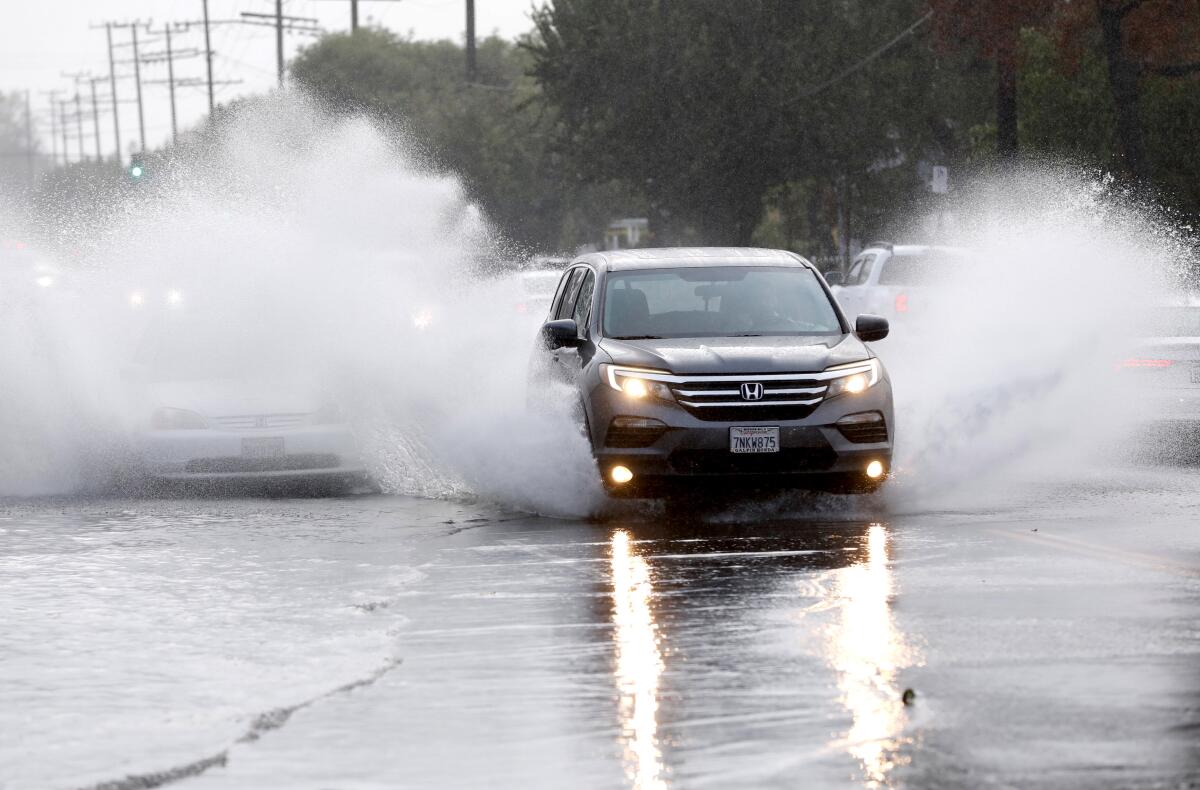Cars fly through standing water on Burbank Boulevard at Louise Avenue in Encino.