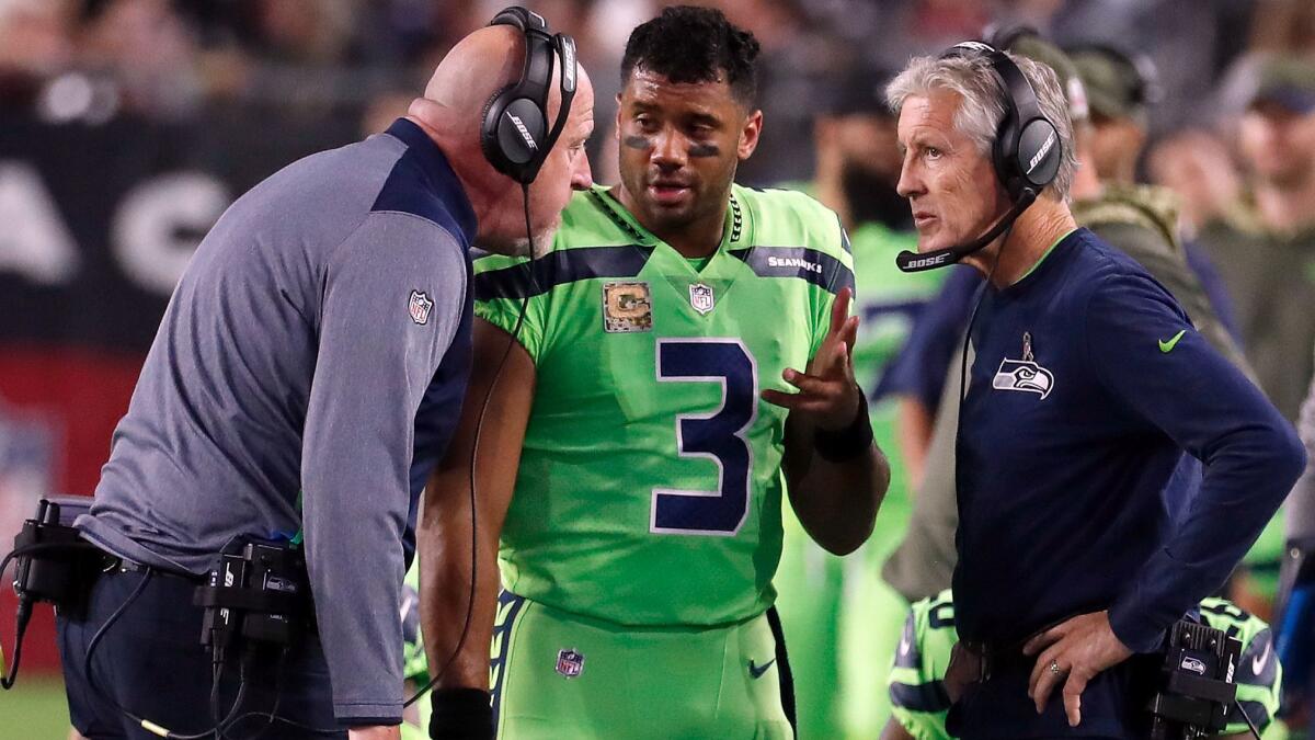 Seattle Seahawks quarterback Russell Wilson speaks with coach Pete Carroll, right, and assistant coach Tom Cable during a game against the Arizona Cardinals on Nov. 9.