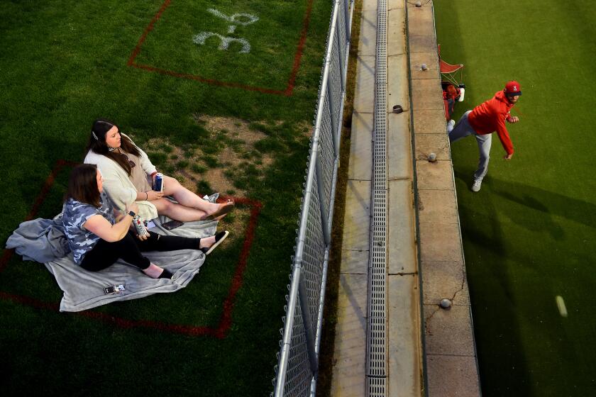 GOODYEAR, ARIZONA MARCH 2, 2021-Fans watch from the outfield as an Angels pitcher warms-up in the bullpen during a game against the Reds at spring training in Goodyear, Arizona Tuesday. (Wally Skalij/Los Angeles Times)