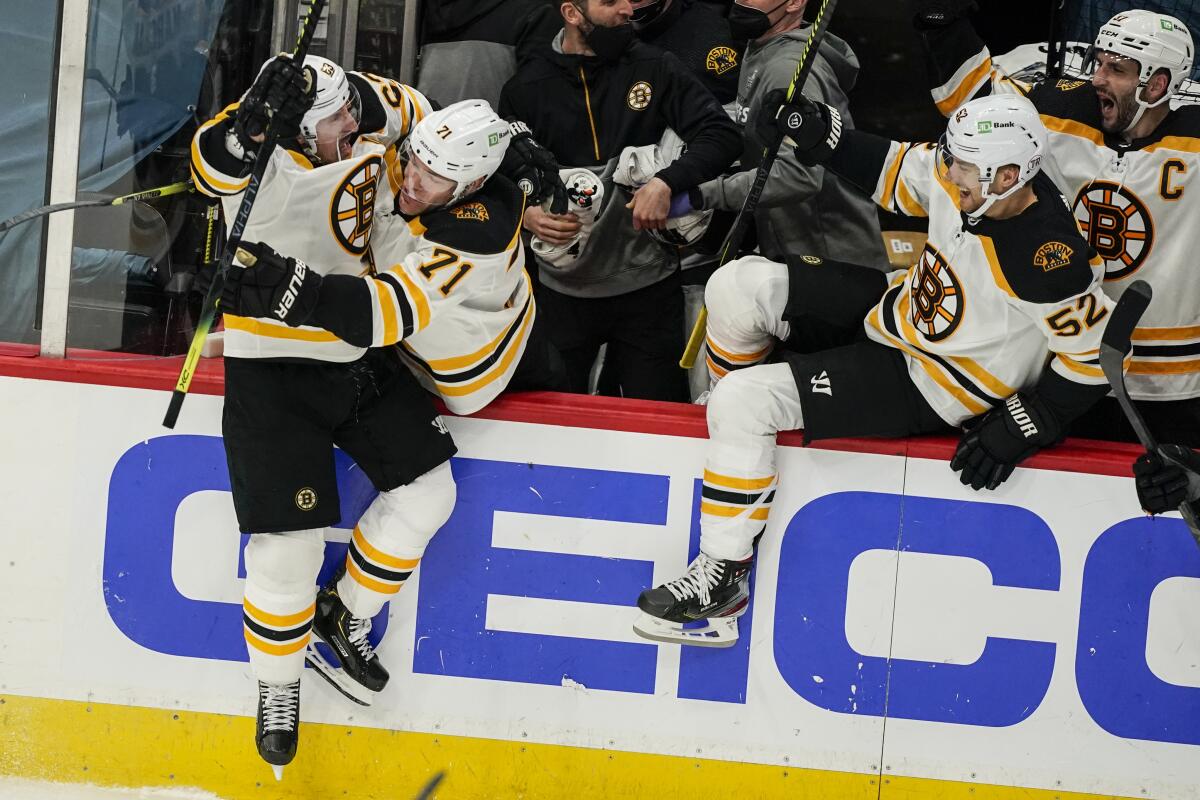 Boston Bruins center Brad Marchand (63) jumps into the arms of left wing Taylor Hall (71) after scoring the winning goal in overtime of Game 2 of an NHL hockey Stanley Cup first-round playoff series against the Washington Capitals, Monday, May 17, 2021, in Washington. (AP Photo/Alex Brandon)