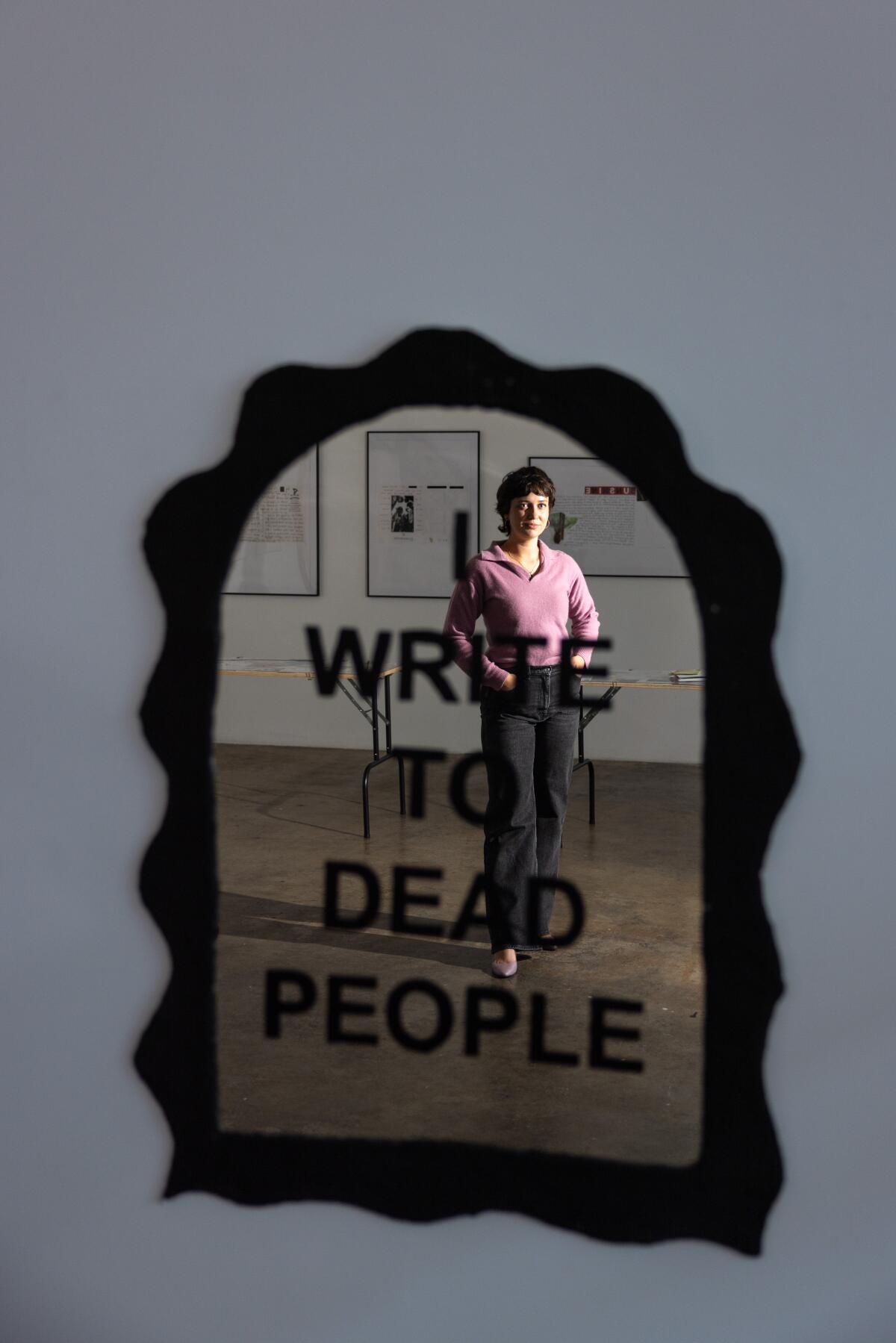 Artist Janelle Ketcher's reflection in a mirror that reads "write to dead people."