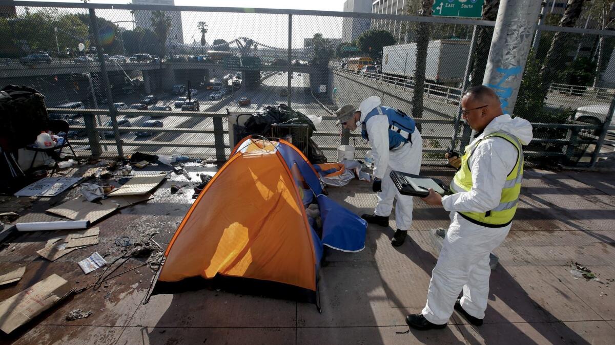 Sanitation and hazmat crews clear out homeless tents on the Main Street overpass above the 101 Freeway on March 15, 2016.