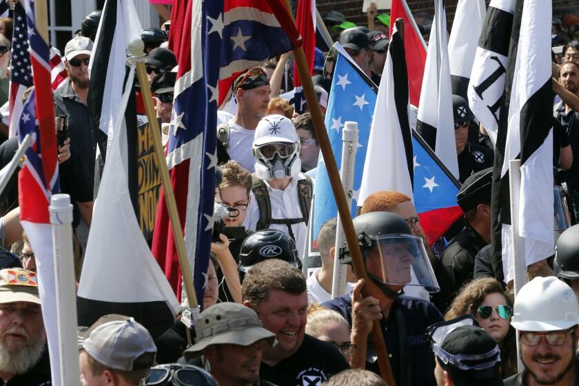 White nationalist demonstrators walk into the entrance of Lee Park surrounded by counter demonstrators in Charlottesville, Va., Saturday, Aug. 12, 2017. Gov. Terry McAuliffe declared a state of emergency and police dressed in riot gear ordered people to disperse after chaotic violent clashes between white nationalists and counter protestors. (AP Photo/Steve Helber)