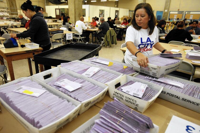 L.A. worker Amy Milo looks over cartons of uncounted ballots from the Los Angeles primary election in Los Angeles.