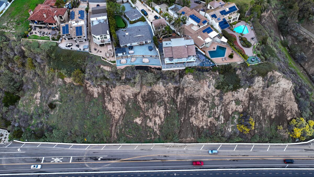 Houses sit on a cliff over a road.