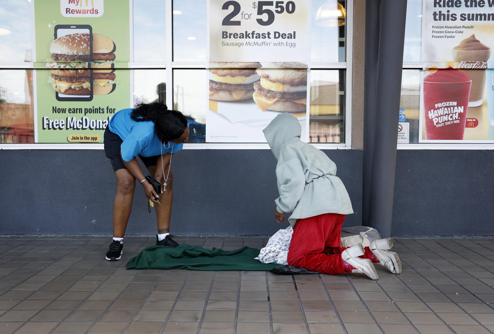 Karen McGee checks in with a woman sleeping outside of a McDonald's restaurant in South Los Angeles.