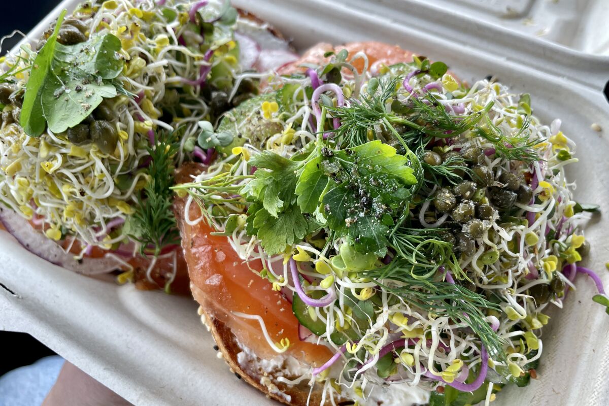 A fully loaded lox sesame bagel topped with sprouts, tomato and more.