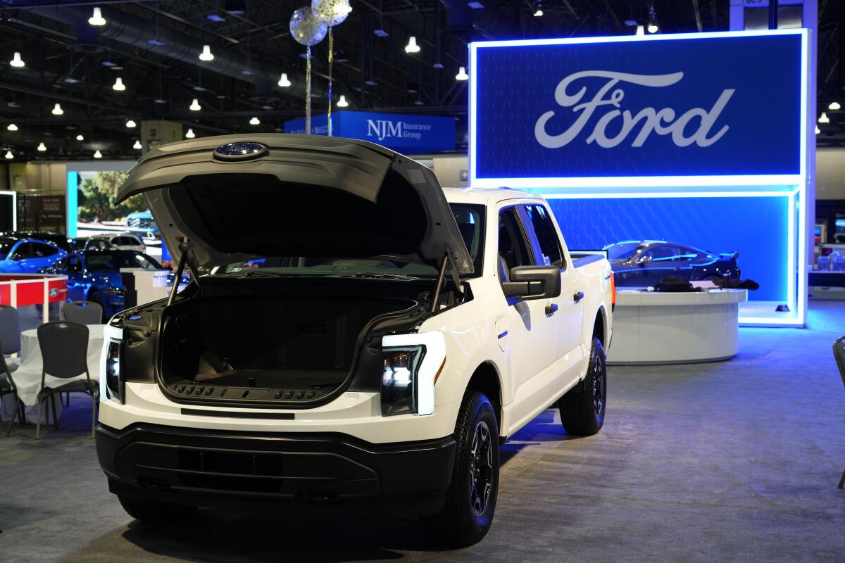 The Ford F-150 Lightning electric pickup truck on display with its hood up.