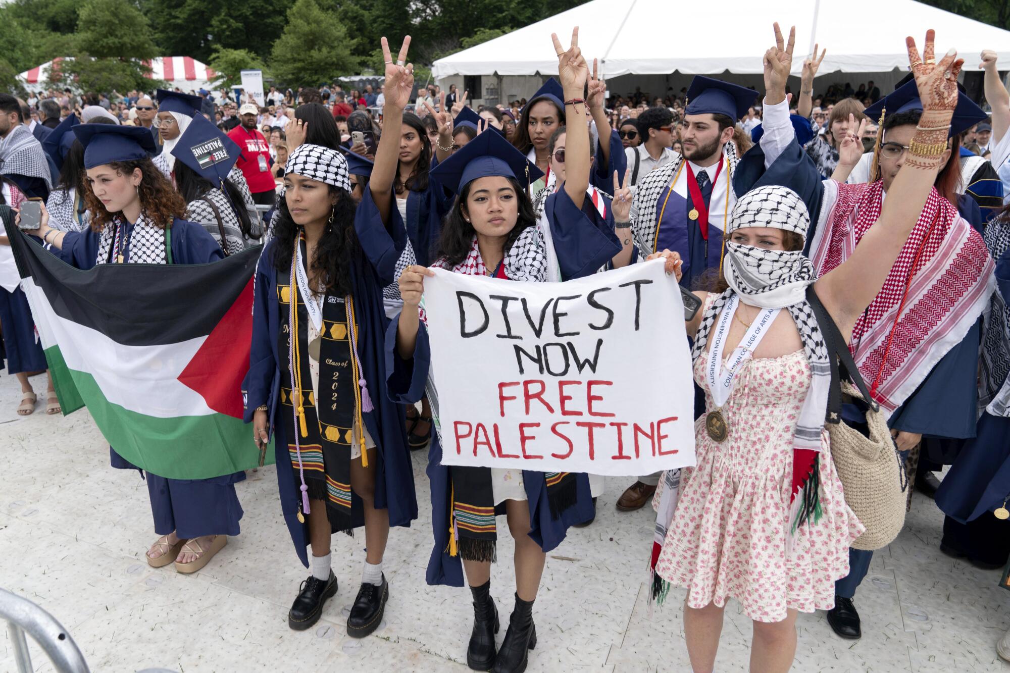Students hold signs and a Palestinian flag during a protest.